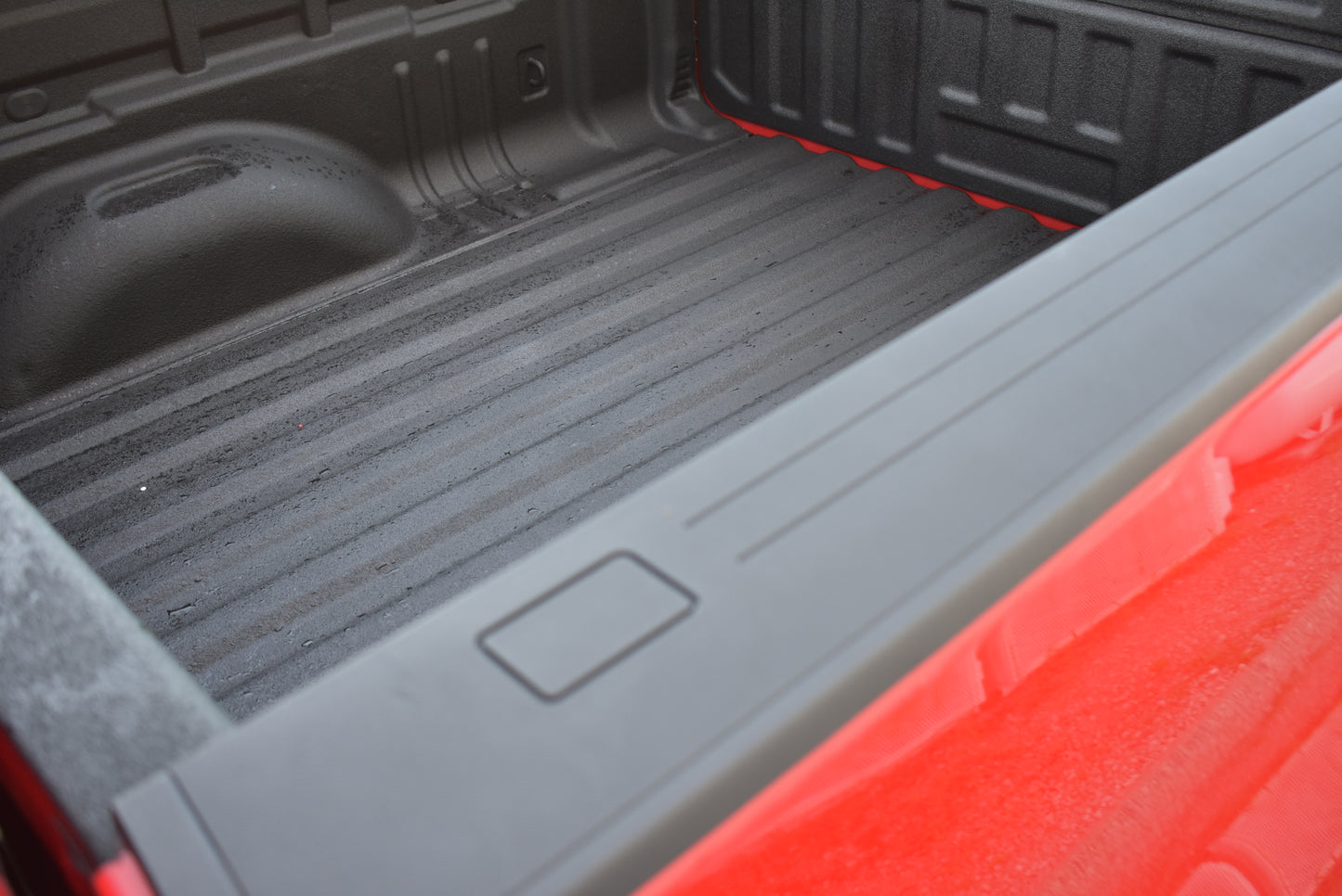 Close-up of a truck bed with a black floor and red sides.
