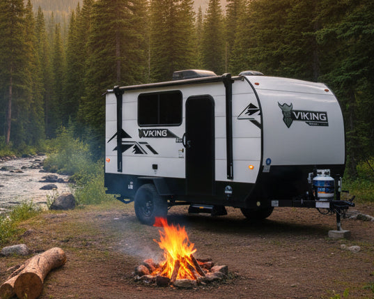 White and black Viking travel trailer parked on grass with trees in the background