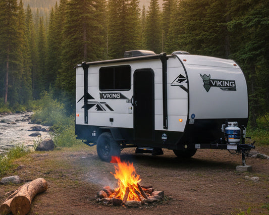 White and black Viking travel trailer parked on grass with trees in the background