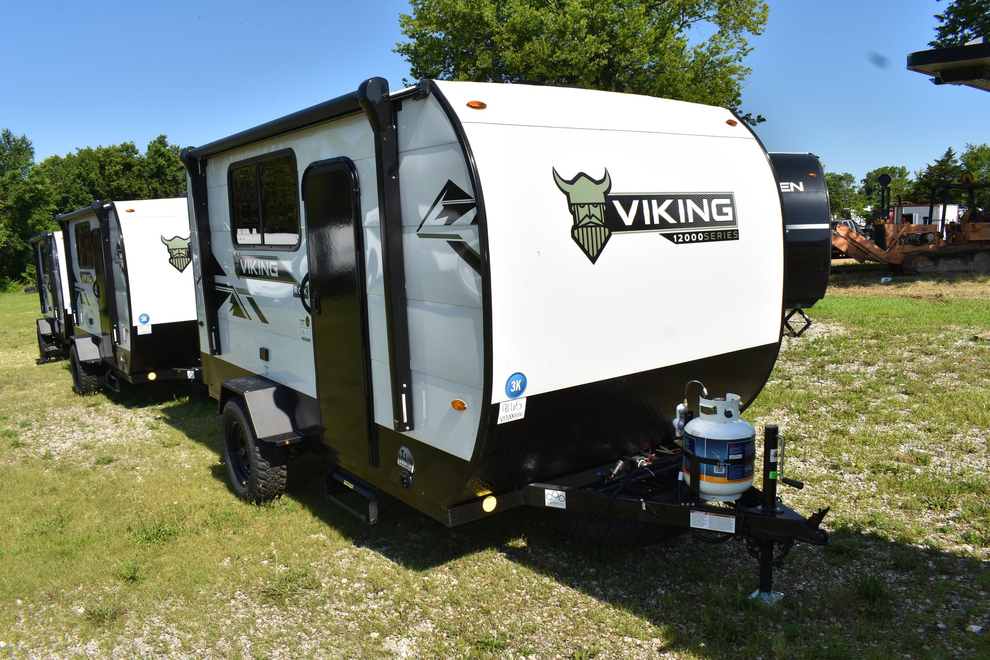 White and black travel trailer with 'Viking' branding parked on grass.