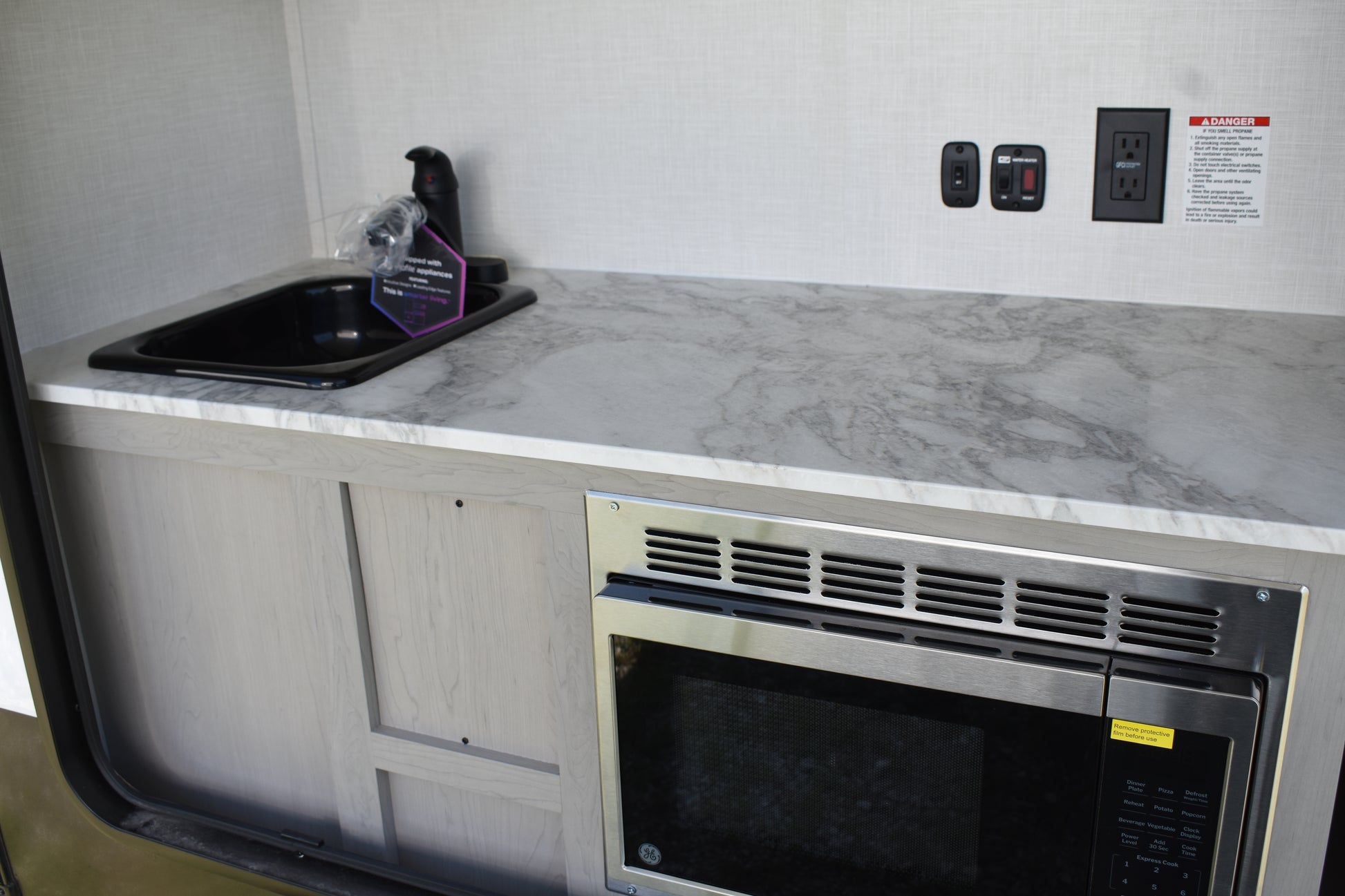 Compact kitchen setup with microwave, sink, and countertop in a small space