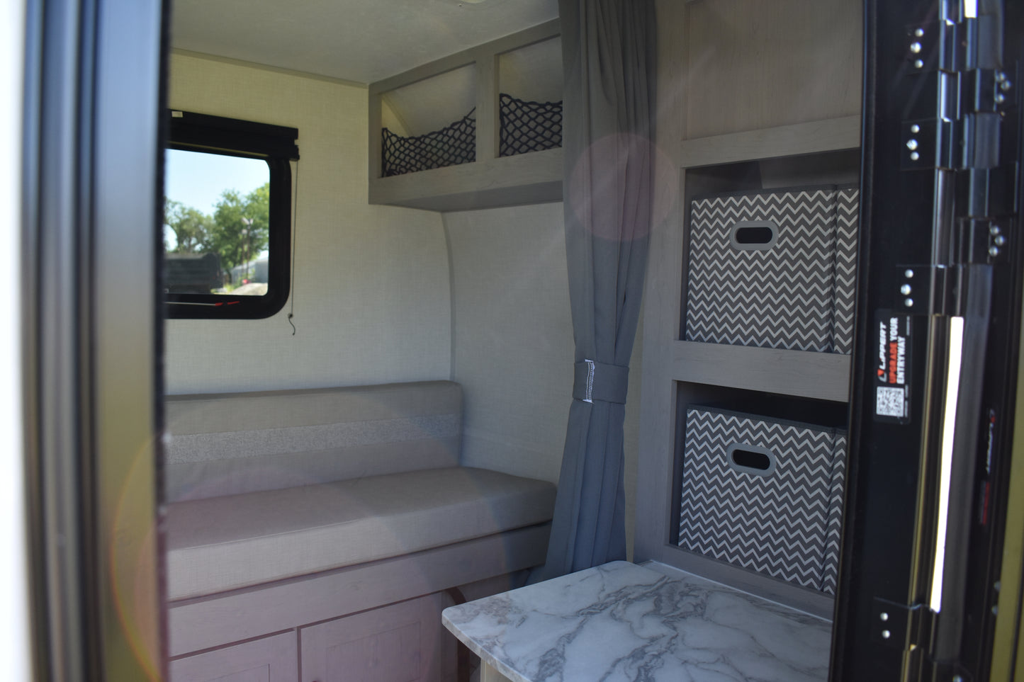 Compact living space inside a vehicle with a bench seat, storage bins, and a window.