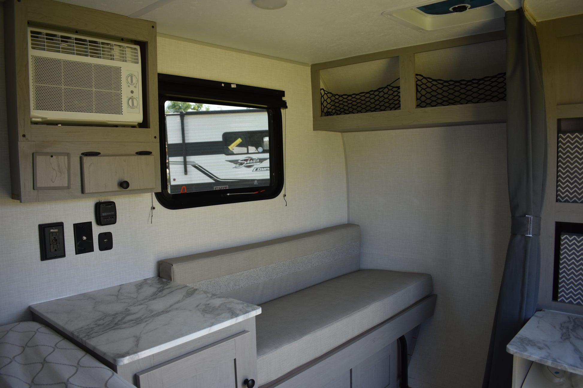 Interior of a compact living space with a bed, table, and small TV.