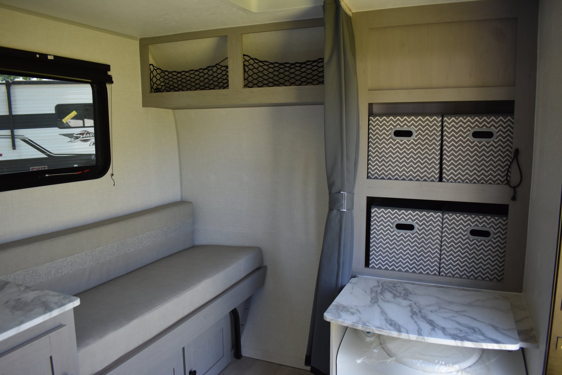 Interior of a compact living space with a bench, storage cabinets, and a window.
