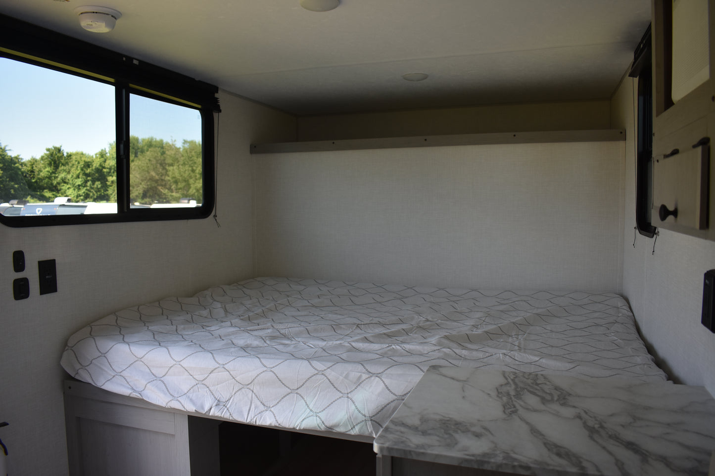 Small bedroom inside a vehicle with a bed and window