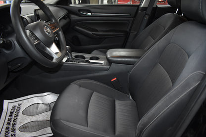 Car interior with steering wheel and dashboard, showing a branded towel on the floor.