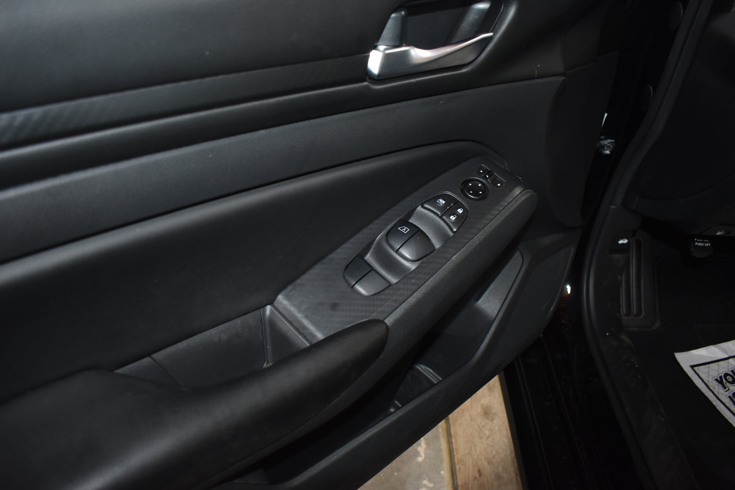 Close-up of a car door interior with controls and handle