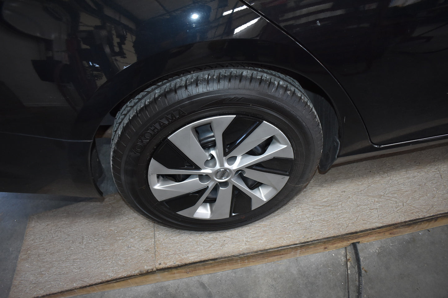 Close-up of a car tire with a shiny silver rim on a black car.