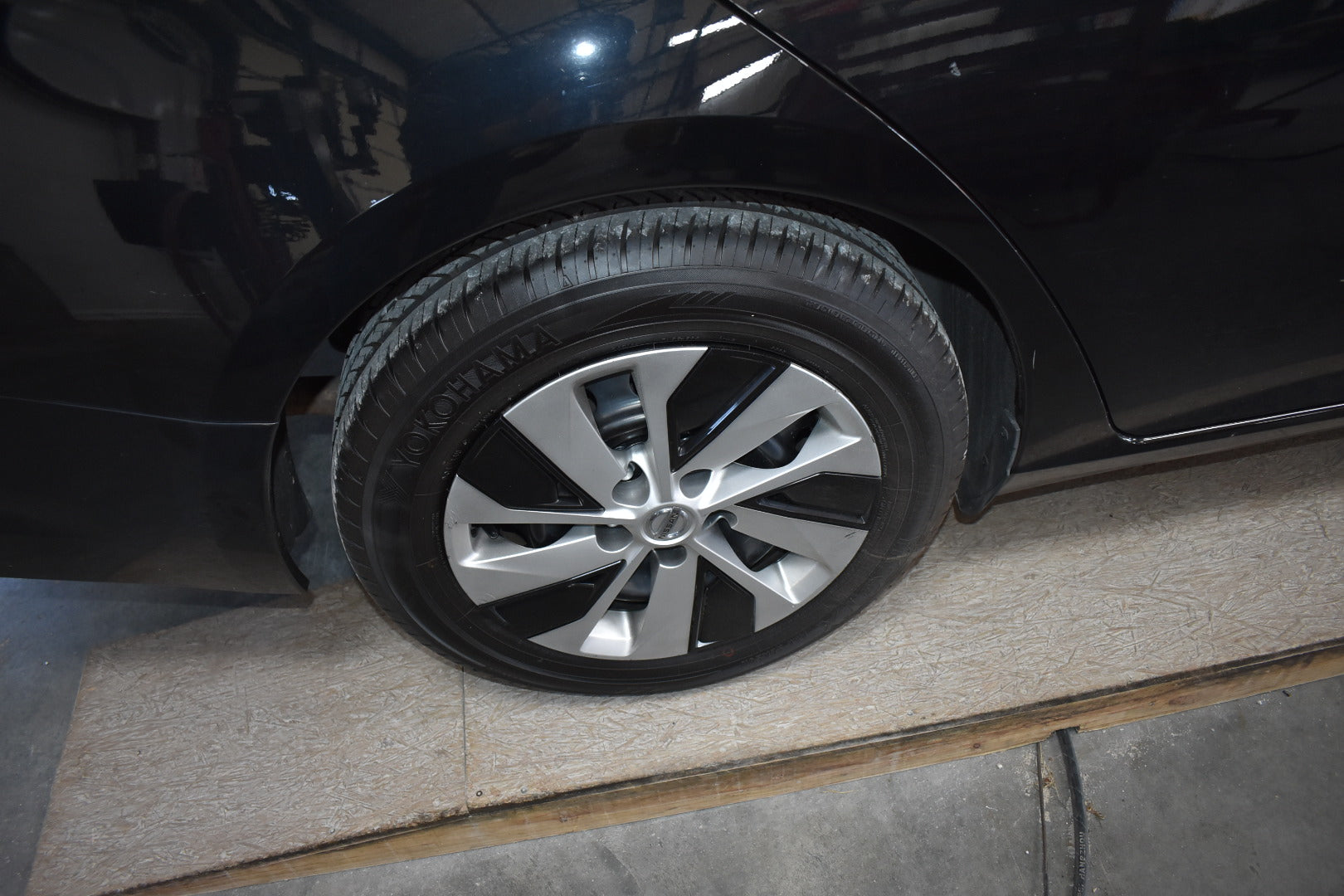 Close-up of a car tire with a shiny silver rim on a black car.