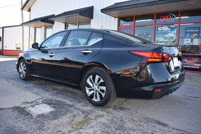 Black car parked in front of a building with a 'Open' sign.