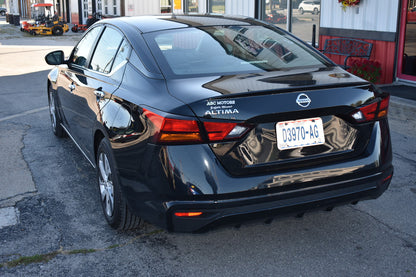 Black Nissan Altima parked on a street with a building in the background