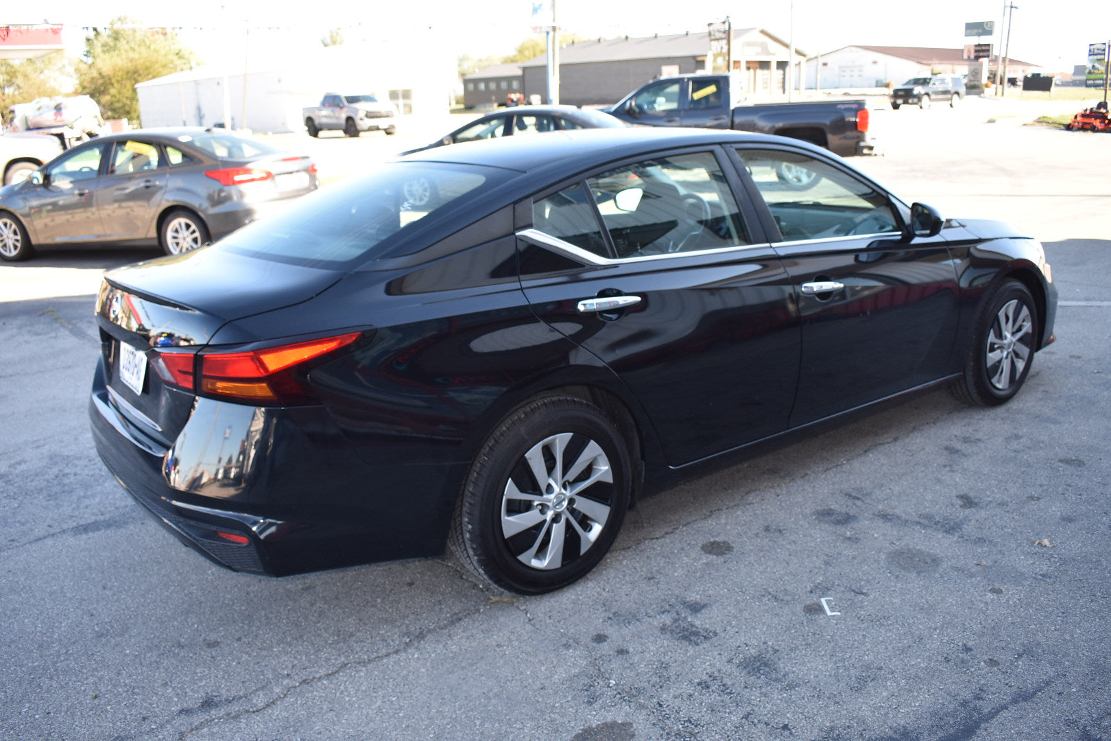 Black sedan parked in a parking lot with other vehicles in the background