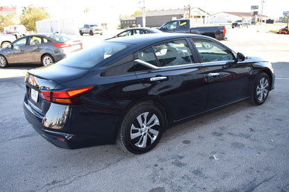 Black sedan parked in a parking lot with other vehicles in the background