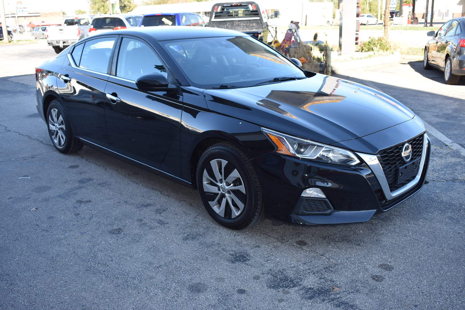 Black sedan car parked on a street with other vehicles in the background