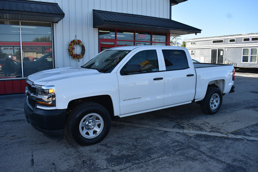 White Chevrolet truck parked in front of a building with a wreath on the door.