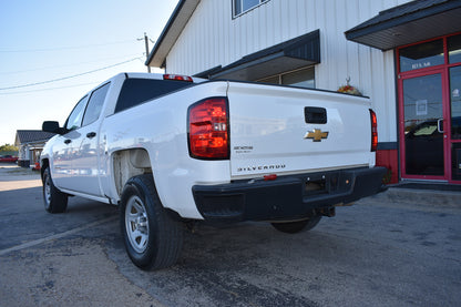White Chevrolet Silverado truck parked in front of a building with a red door.