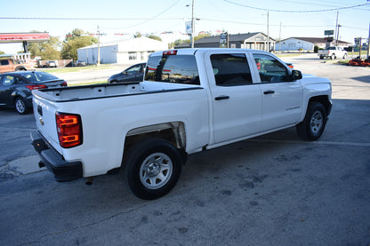 White pickup truck parked in a lot with buildings and cars in the background