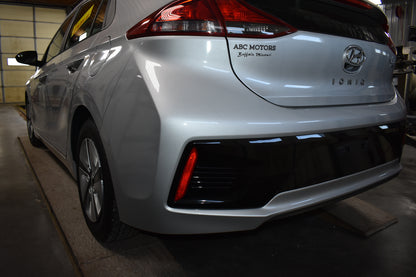 White Hyundai Ioniq electric vehicle in a garage with 'ABC MOTORS' branding.