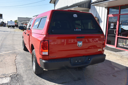 Red pickup truck parked on a street with a building in the background