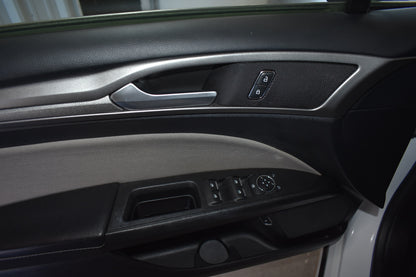 Close-up of a car's interior door panel with controls and handle.