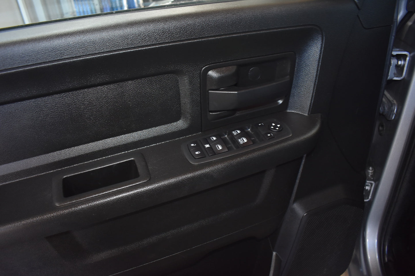 Close-up of a car door panel with controls and switches.