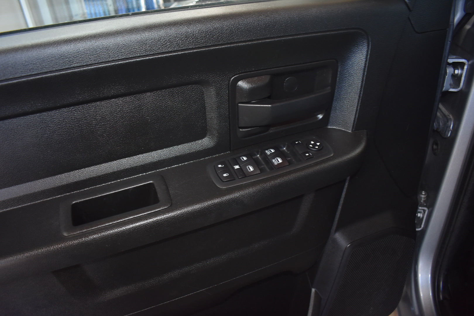 Close-up of a car door panel with controls and switches.