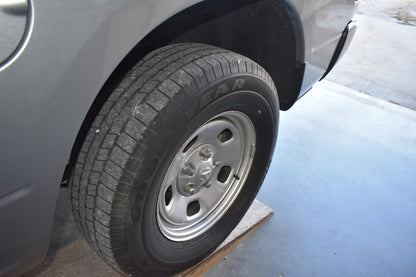 Car tire with visible tread pattern on a gray pavement