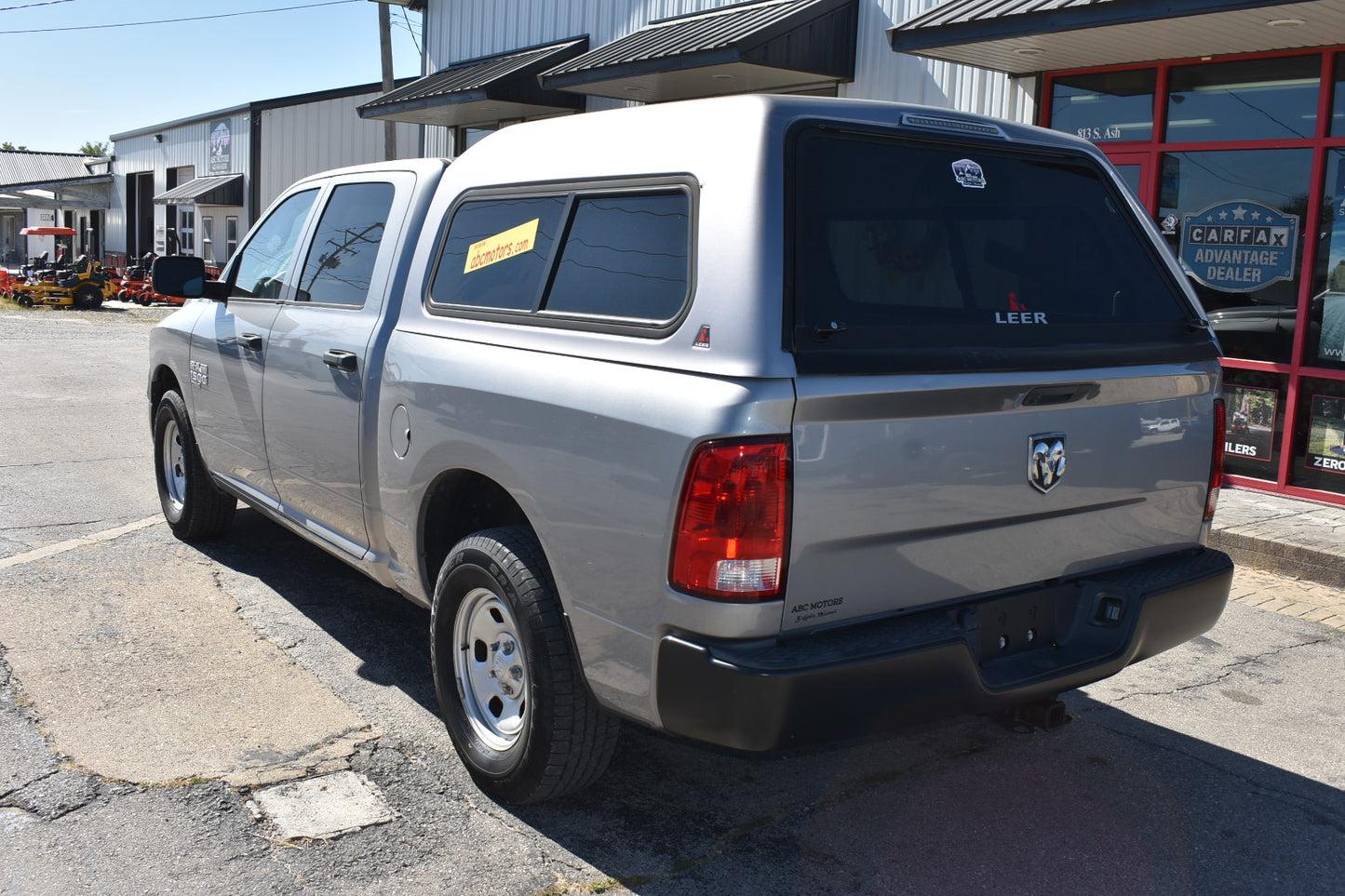 Silver pickup truck with a black tonneau cover parked in front of a building.