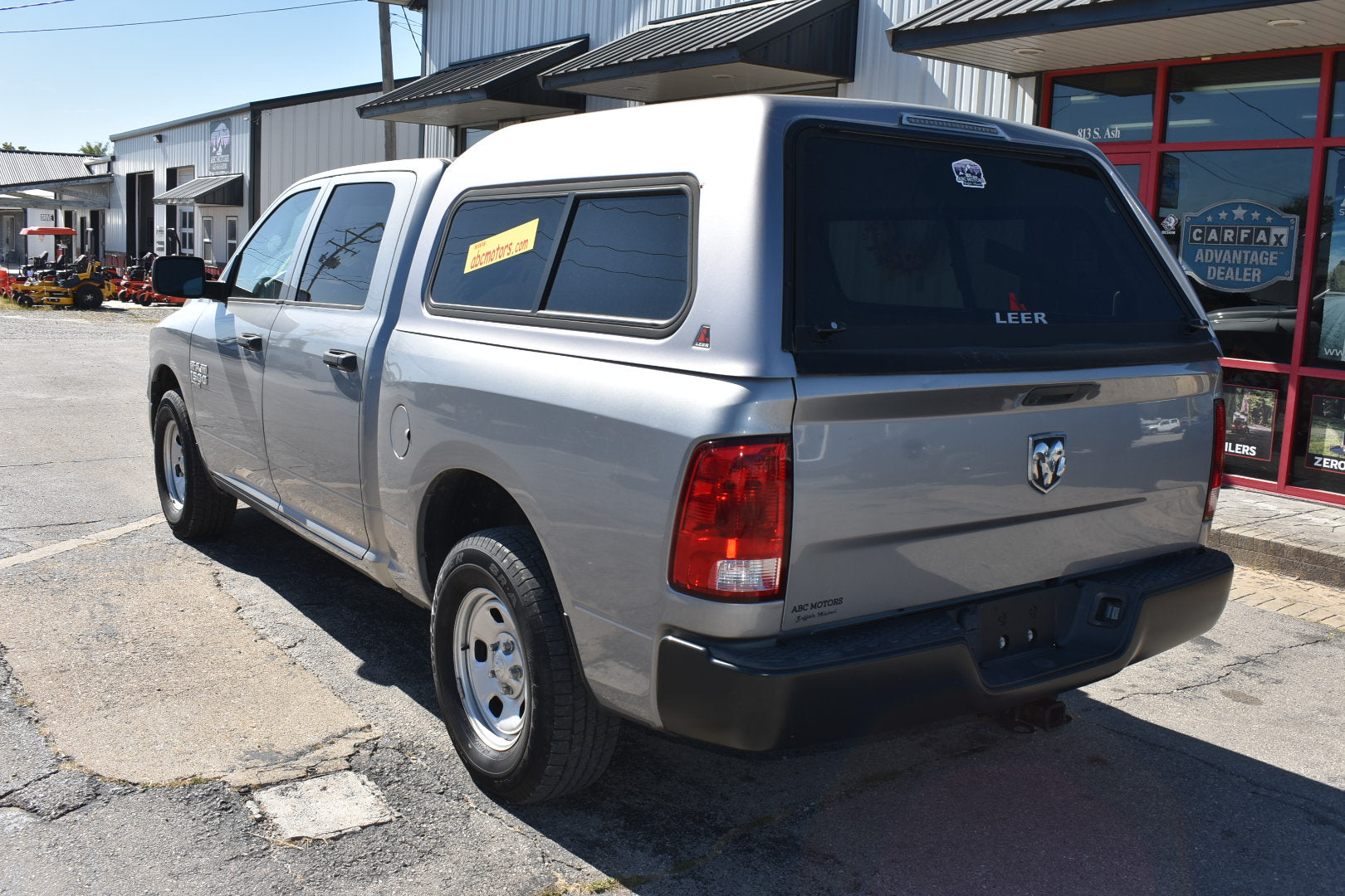Silver pickup truck with a black tonneau cover parked in front of a building.
