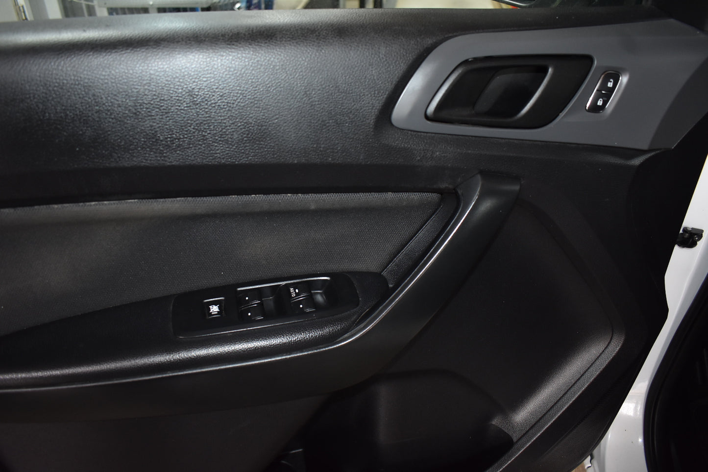 Close-up of a car door panel with controls and speaker.