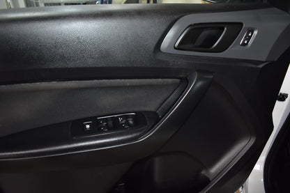 Close-up of a car door panel with controls and speaker.