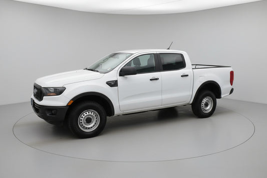 White pickup truck parked in front of a building with a wreath on the door.