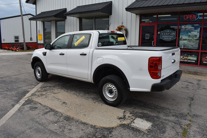 White pickup truck parked in front of a building with a 'Open' sign.
