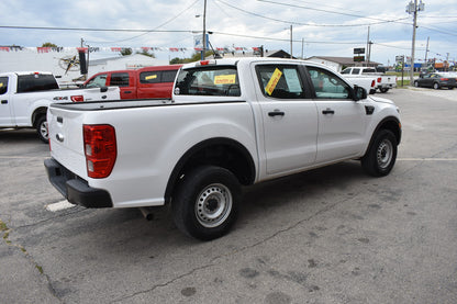White pickup truck in a lot with other vehicles and a cloudy sky.