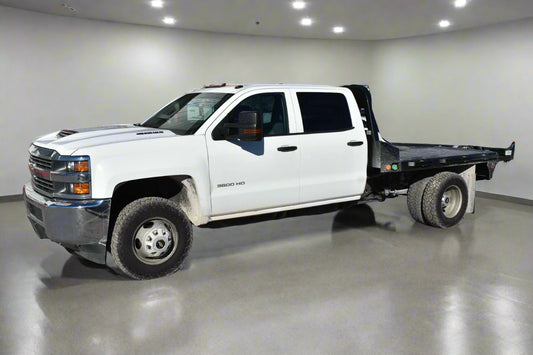 White pickup truck with a flatbed in front of a building with a sign that reads 'Carfax'.