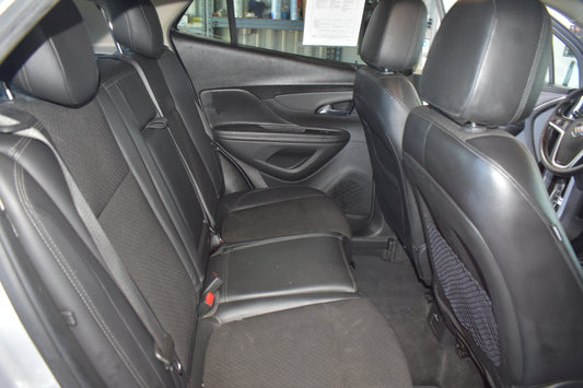 Rear passenger seat and front driver seat of a black car interior, showing the backrest, center armrest, door panel, and part of the steering wheel.
