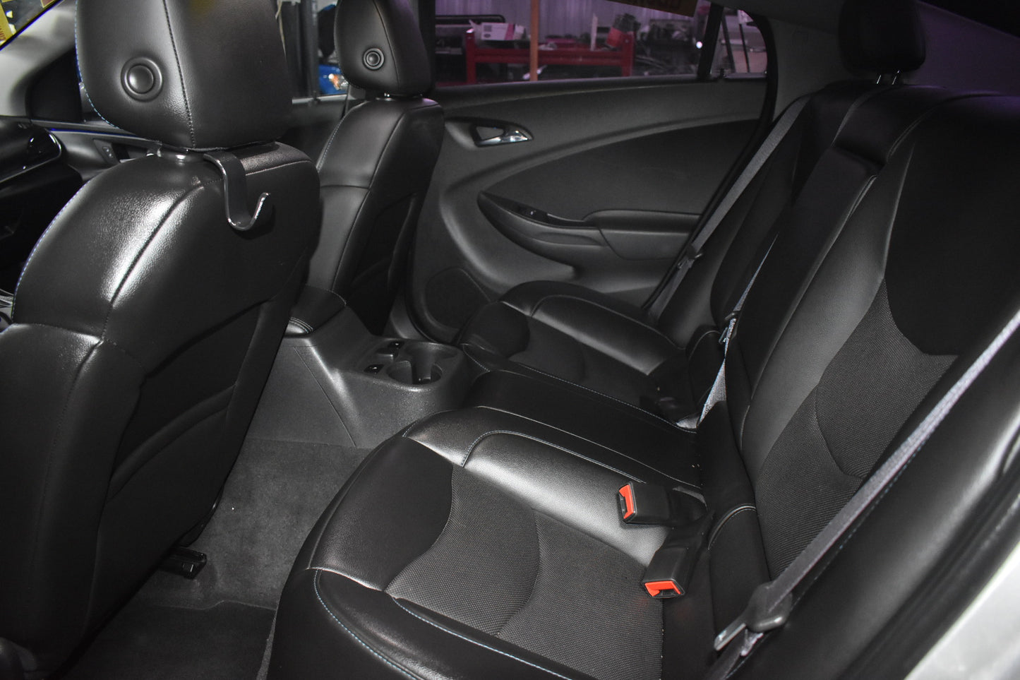 Car interior with black leather seats and visible seat belts.