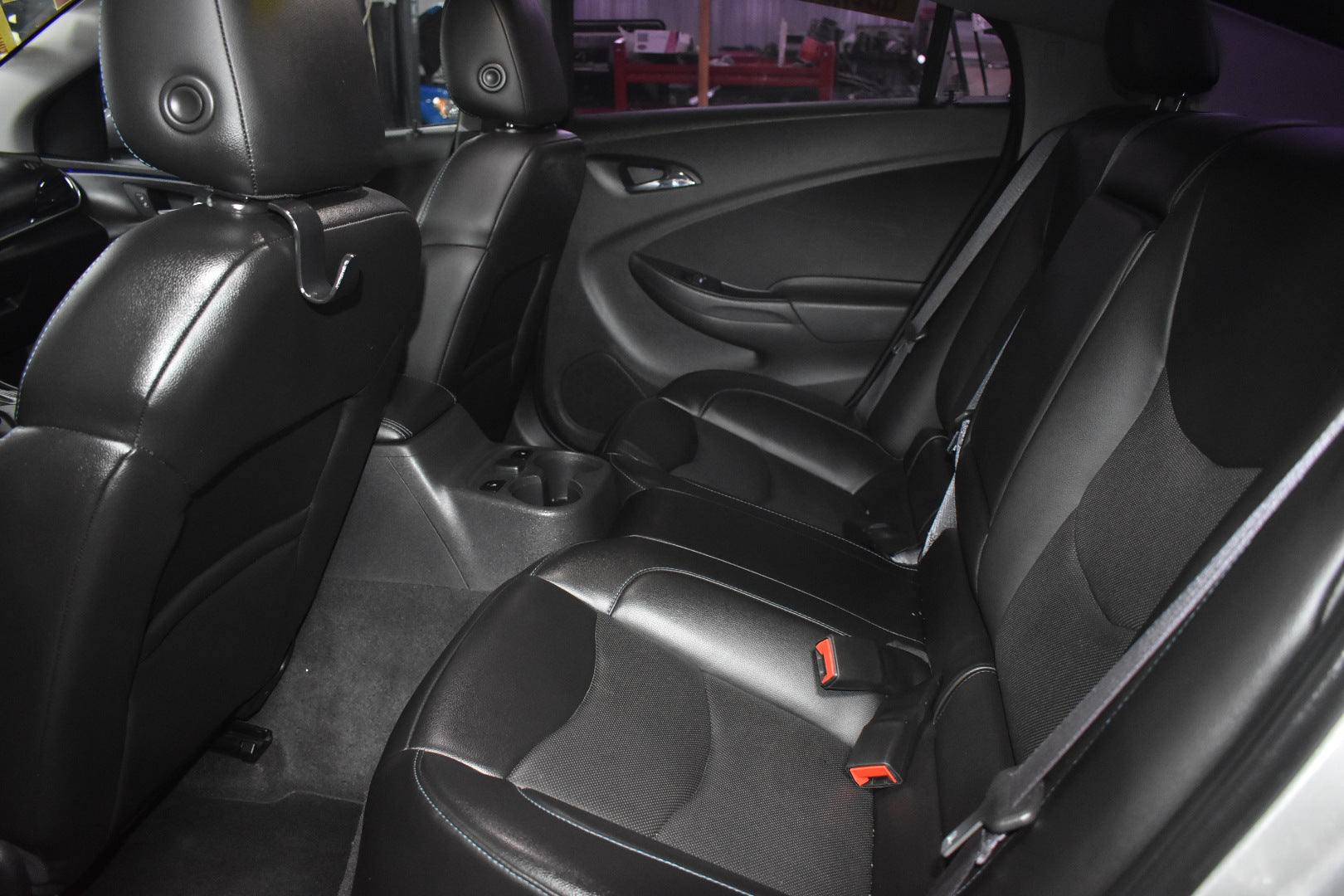Car interior with black leather seats and visible seat belts.