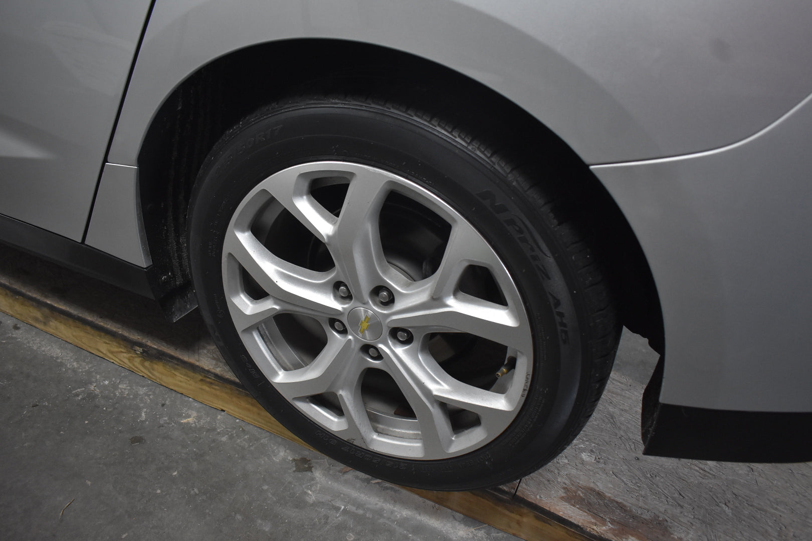 Close-up of a car wheel with a silver rim on a gray vehicle.
