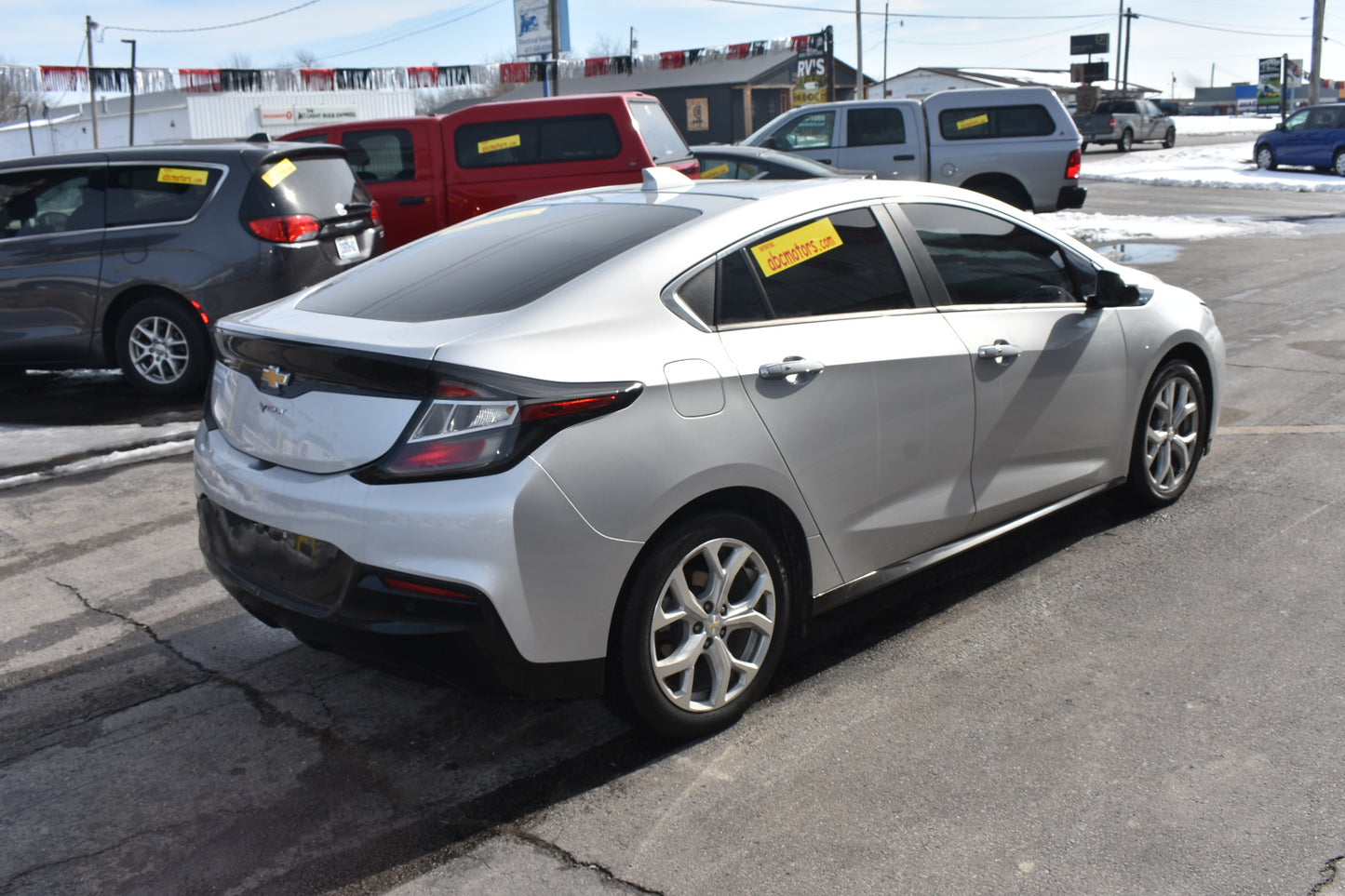 White car parked in a lot with other vehicles in the background