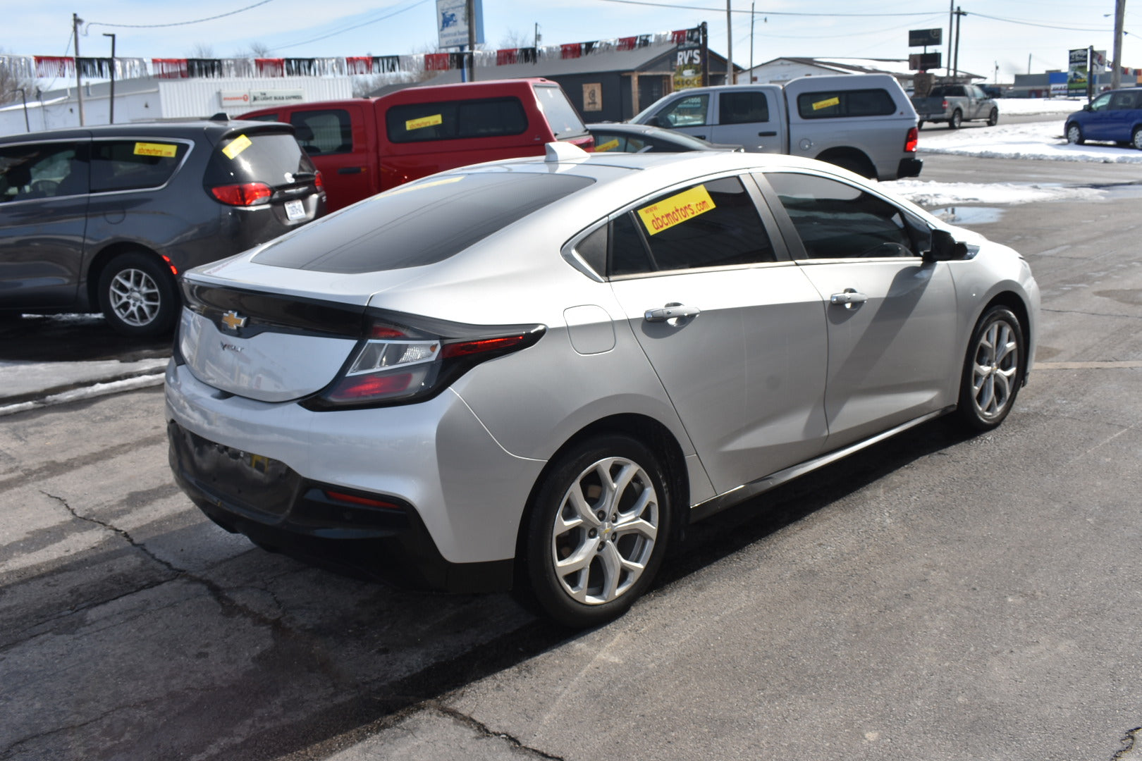 White car parked in a lot with other vehicles in the background