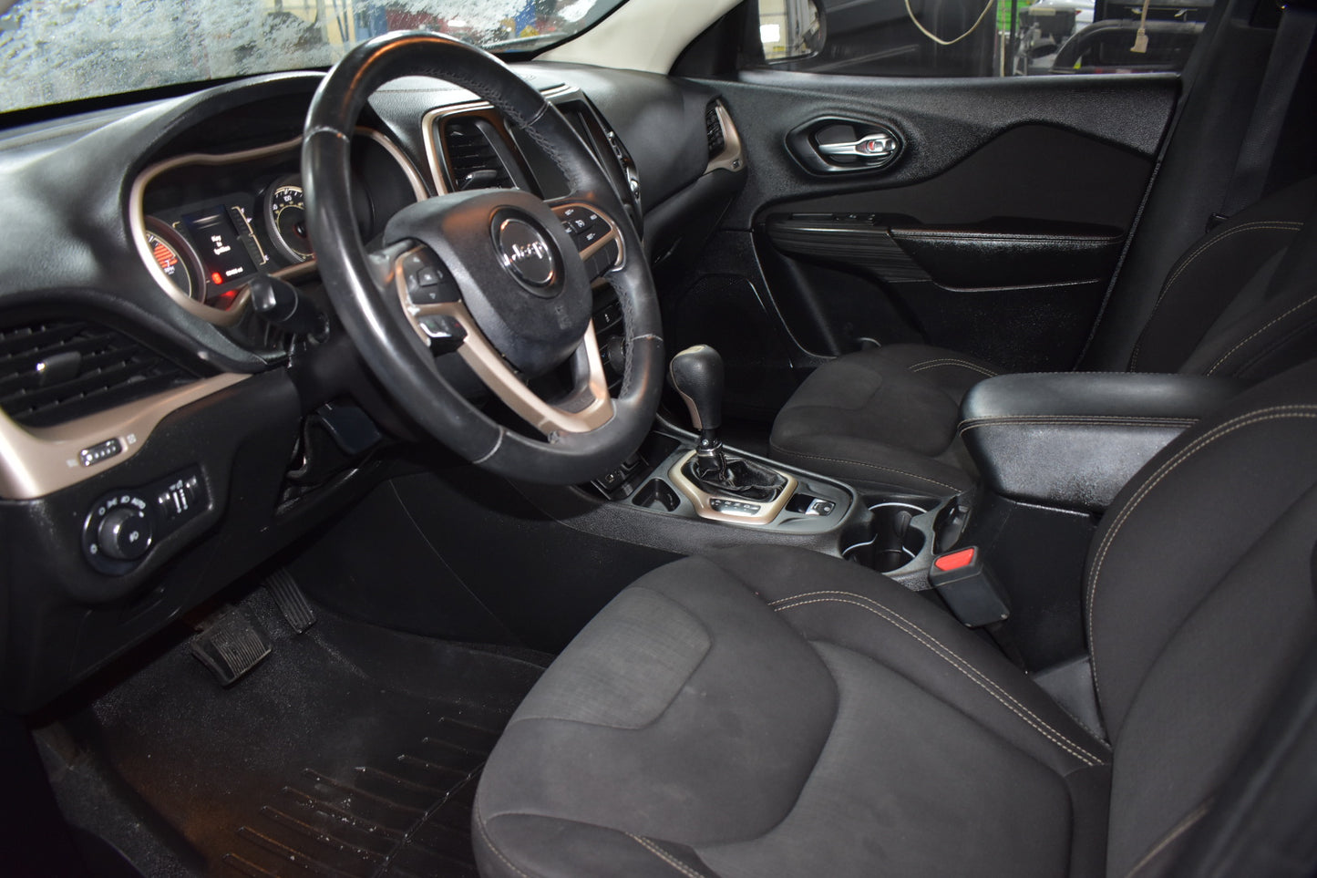 Car interior with steering wheel, dashboard, and seats.