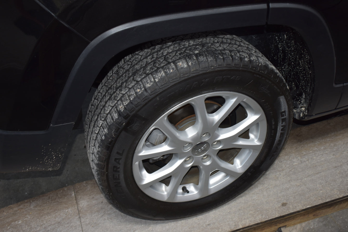 Close-up of a car tire with a visible brand logo on a black vehicle.