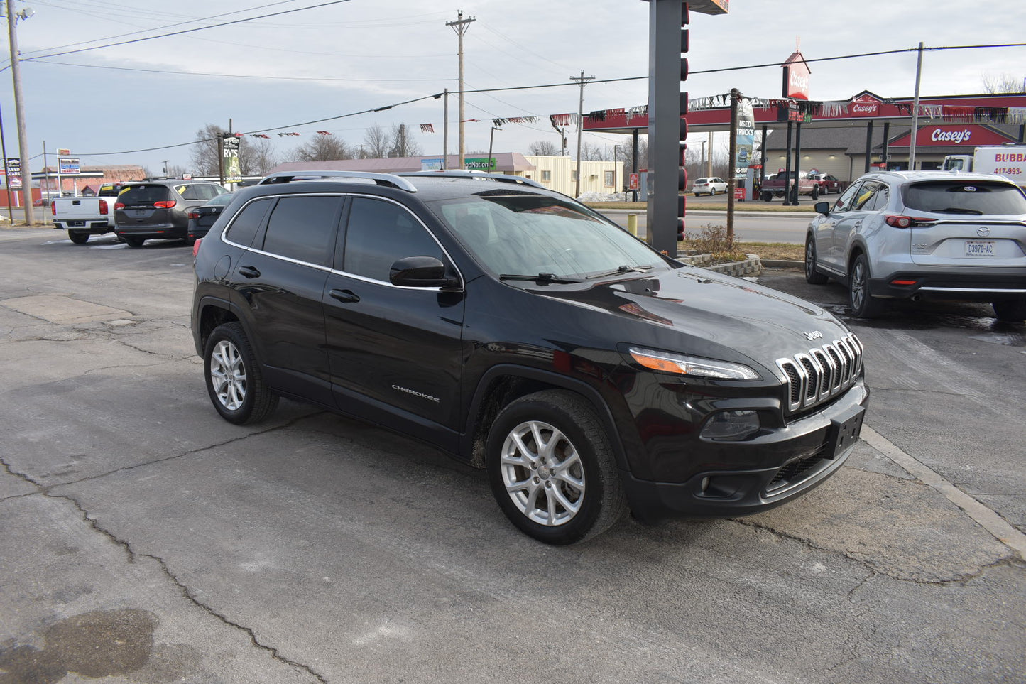 Black SUV parked on a street with a gas station in the background
