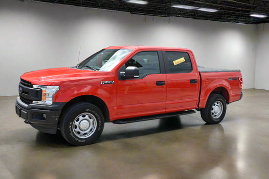 Red pickup truck parked in front of a car dealership