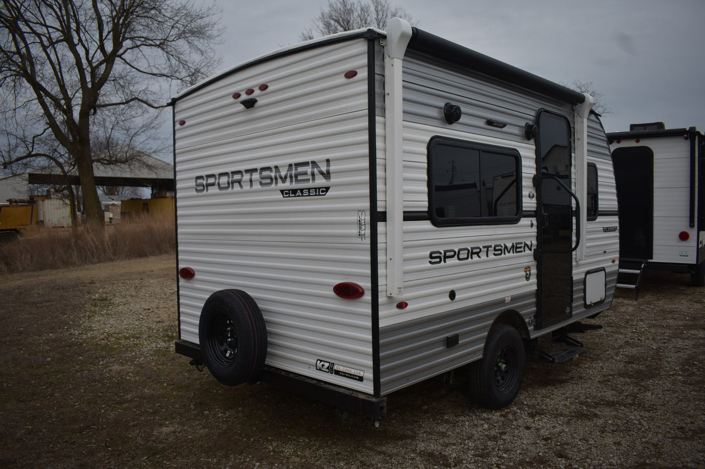 White Sportsmen travel trailer parked outdoors on a cloudy day