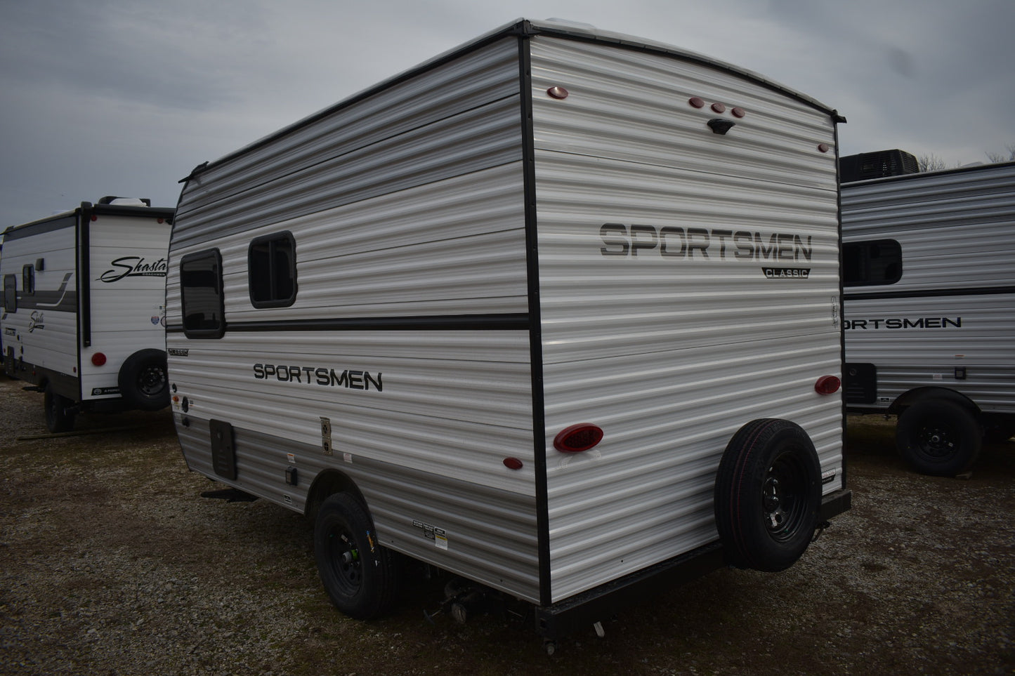 White travel trailer with 'Sportsmen' branding on a cloudy day.
