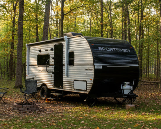 Travel trailer with 'Sportmen' branding on a grassy area