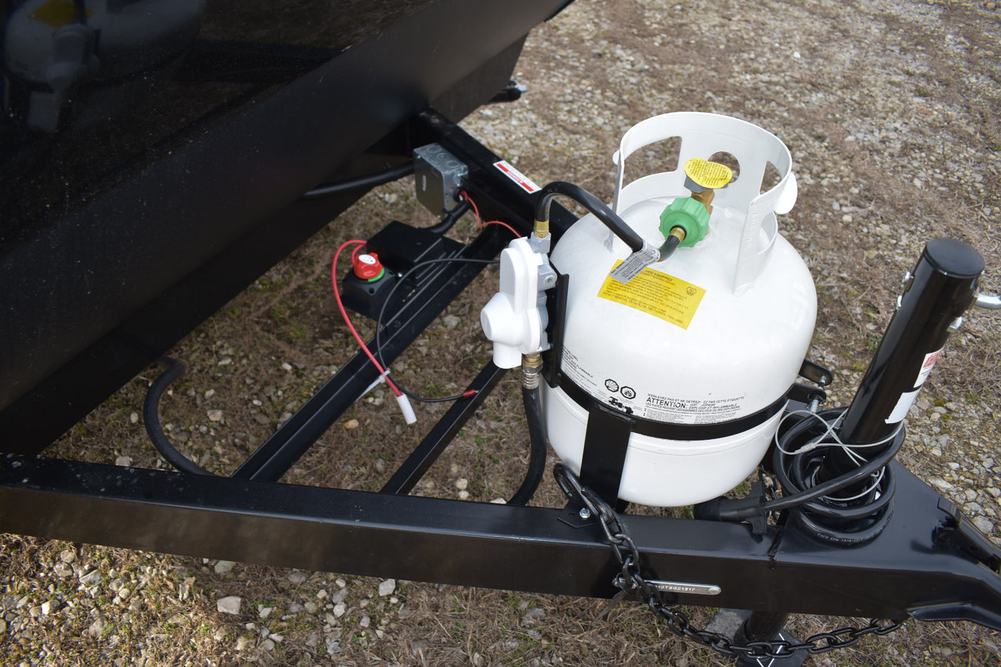 Propane tank attached to a trailer with wiring and attachments.