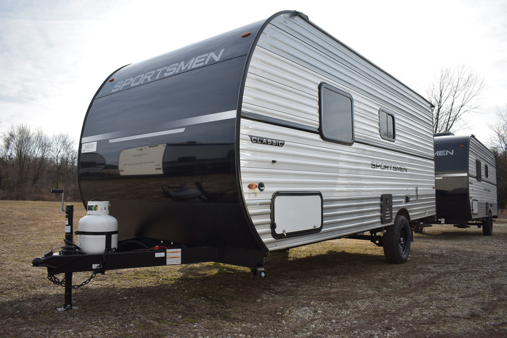 Travel trailer with 'Sportsmen' branding on a dirt road.